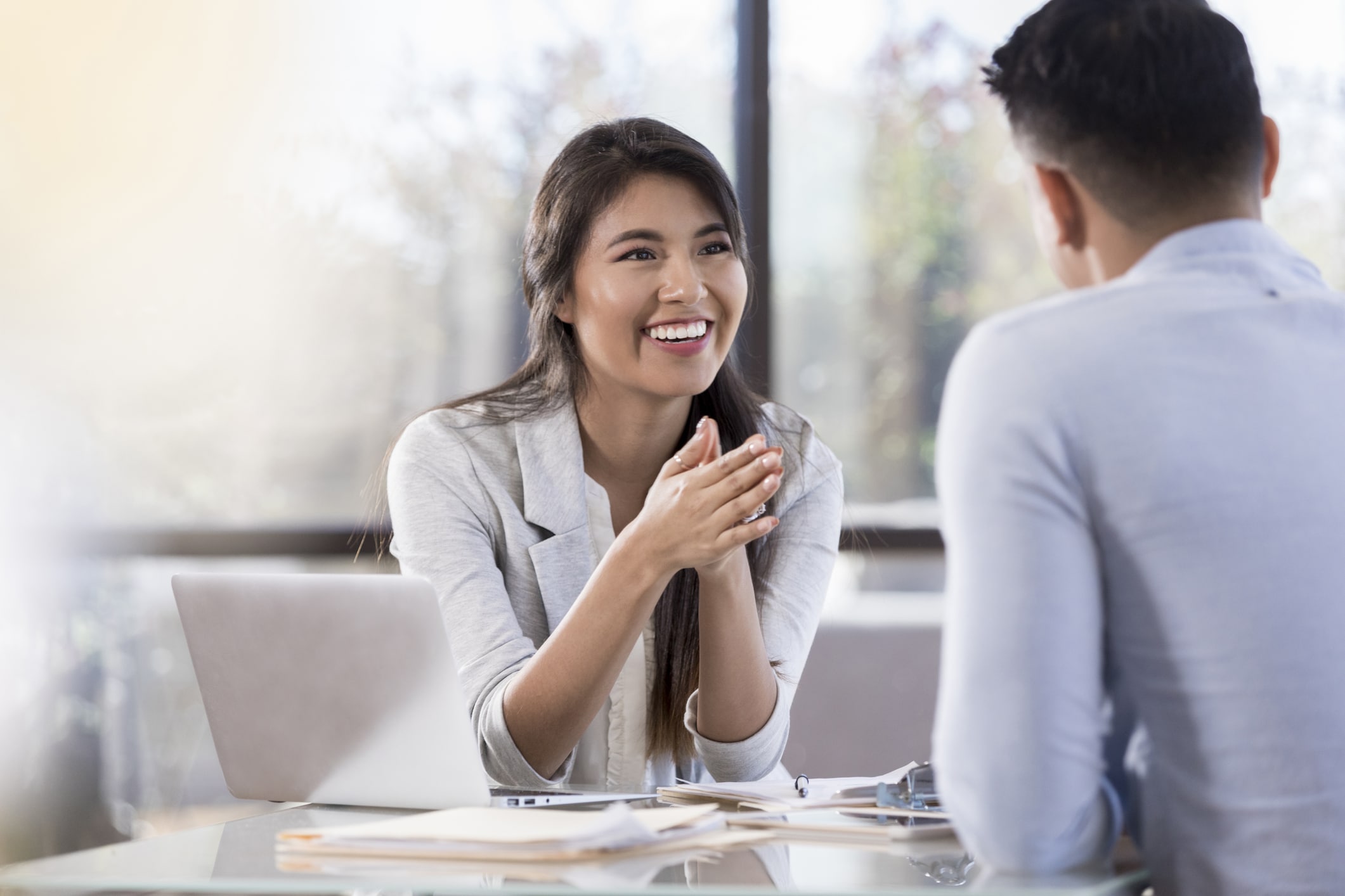 Cheerful buisnesswoman meets with colleague Smiling young Hispanic businesswoman meets with a male colleague.